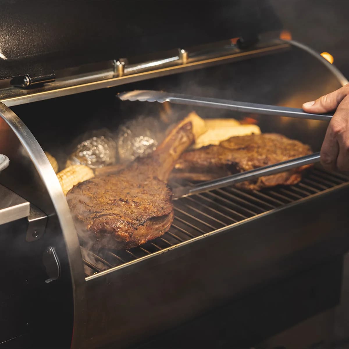 A thick ribeye being turned with tongs on a Road Warrior